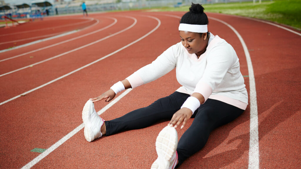 AA women's perspective on weight loss - AA female stretching on track field